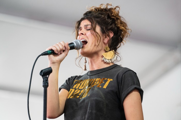 Une femme en T-shirt noir chante intensément dans un micro